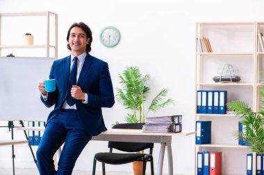 Genç işadamı ofiste oturuyor ve çalışıyor.