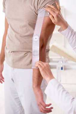 Kadın doktor hastaları goniyometre ile kontrol ediyor.