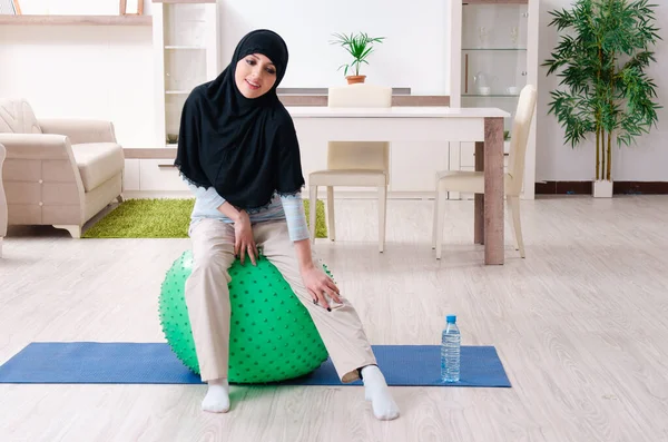 Jonge vrouw in hijab doet oefeningen thuis — Stockfoto