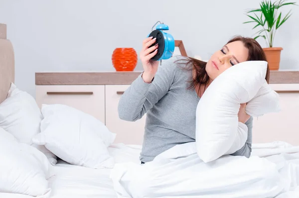 Mujer joven acostada en la cama en concepto de gestión del tiempo — Foto de Stock