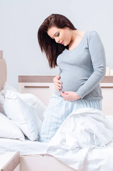 Jonge zwangere vrouw in de slaapkamer — Stockfoto