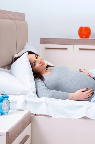 Mladá těhotná žena v ložnici — Stock fotografie