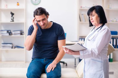 Genç erkek hasta yaşlı kadın doktoru ziyaret ediyor.