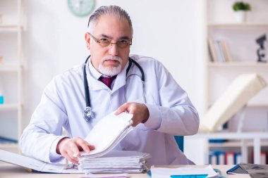 Klinikte çalışan yaşlı erkek doktor.