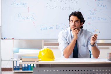 Genç erkek mimar beyaz tahtanın önünde.