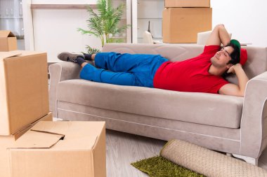 İçeride çalışan kutularla çalışan genç bir erkek müteahhit.