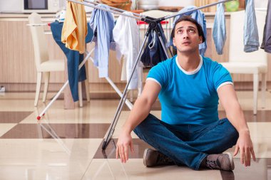 Genç adam evde çamaşır ütülüyor.