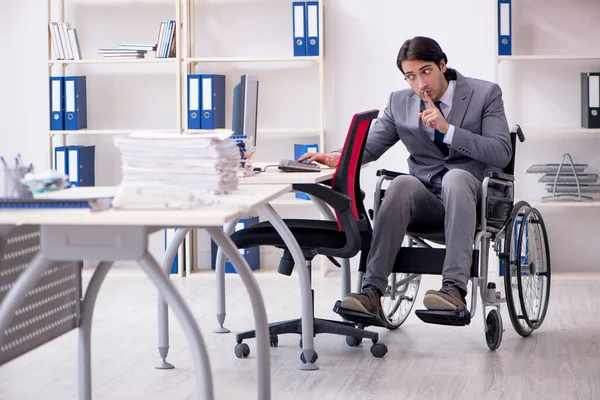 Jonge knappe werknemer in rolstoel werkt in het kantoor — Stockfoto