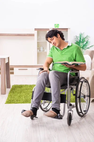 Joven hombre guapo en silla de ruedas en casa —  Fotos de Stock