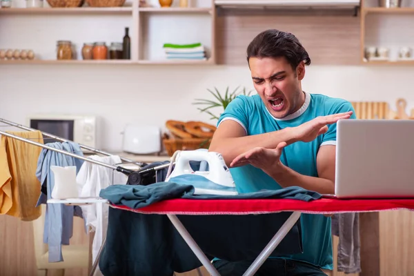 Genç adam evde çamaşır ütülüyor.