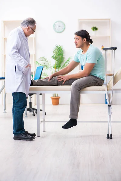 Jovem perna machucado paciente masculino visitando antigo médico — Fotografia de Stock