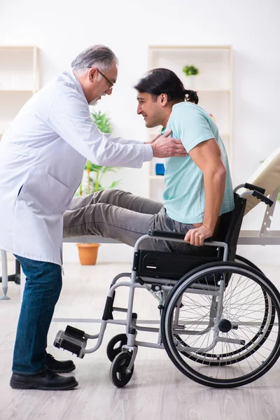 Paciente masculino en silla de ruedas visitando a un viejo médico — Foto de Stock