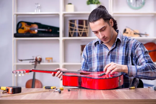 Junger gutaussehender Reparateur repariert Gitarre — Stockfoto