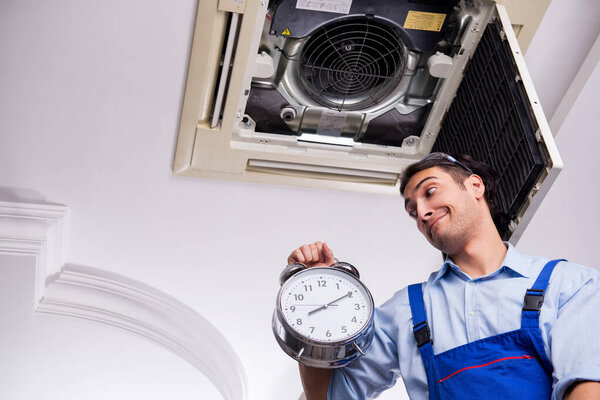 Молодой ремонтник ремонтирует потолочные кондиционеры