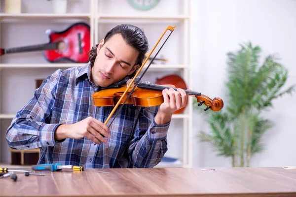 Jovem reparador bonito reparando violino — Fotografia de Stock