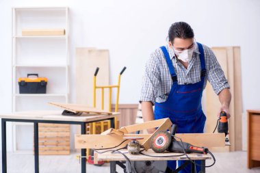 Genç erkek marangoz içeride çalışıyor.