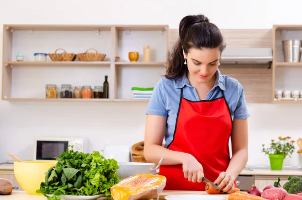 Ung kvinna med grönsaker i köket — Stockfoto