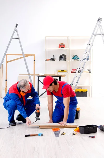 Two professional contractors laying flooring at home