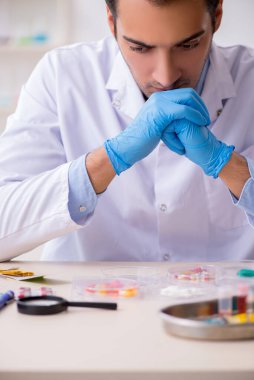 Uyuşturucu sentezi konseptinde genç erkek laboratuvar asistanı