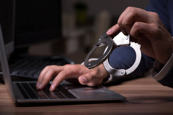 Male hacker hacking security firewall late in office