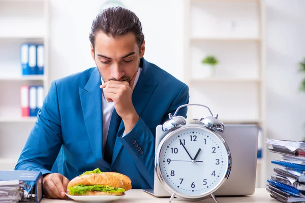 Jeune employé masculin prenant son petit déjeuner sur le lieu de travail — Photo