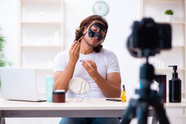 Genç erkek kozmetikçi blogu için video kaydediyor.