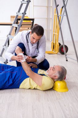 İlk yardım konseptinde genç erkek doktor ve yaşlı müteahhit.