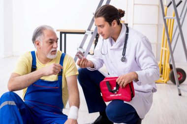 İlk yardım konseptinde genç erkek doktor ve yaşlı müteahhit.