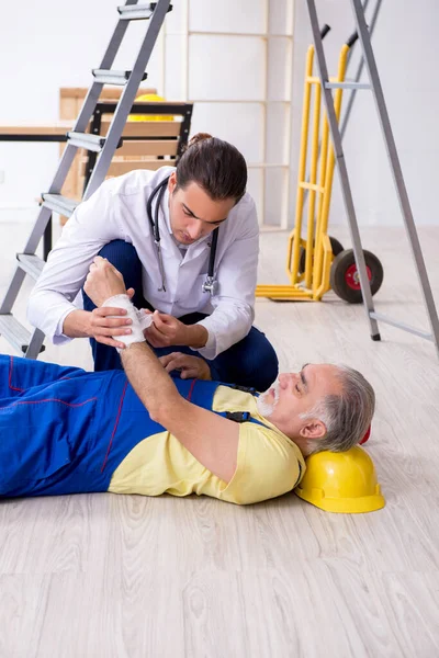 Young male doctor and old contractor in first aid concept — Stock Photo, Image
