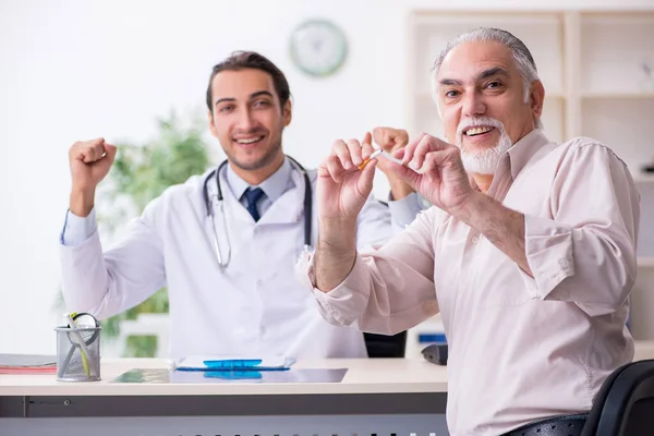 Joven médico masculino y paciente de edad avanzada en concepto antitabaco — Foto de Stock