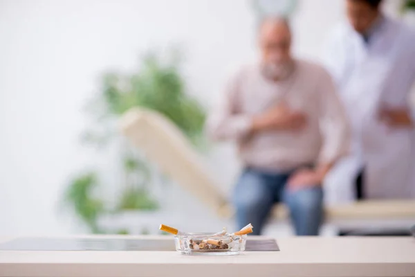 Sigara karşıtı genç erkek doktor ve yaşlı hasta — Stok fotoğraf