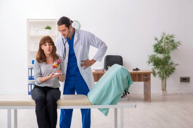 Genç bir kadın erkek doktor kardiyoloğu ziyaret ediyor.