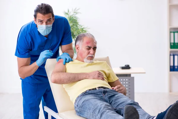 Skadad gammal man besöker ung manlig läkare traumatolog — Stockfoto