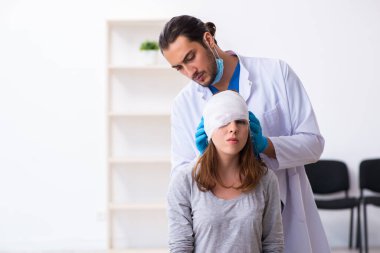 Genç baş yaralı kadın genç erkek doktoru ziyaret ediyor.