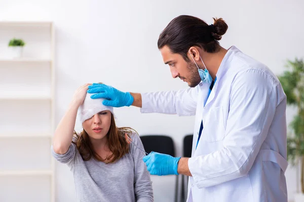 Joven cabeza lesionada mujer visitando joven médico masculino —  Fotos de Stock