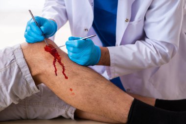 Yaralı adam ilk yardım konseptinde yaşlı doktoru ziyaret ediyor.