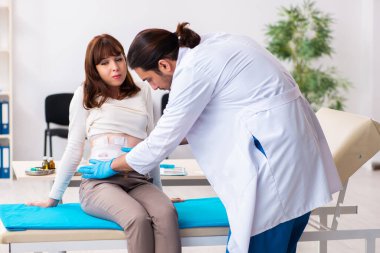 Yaralı genç kadın genç erkek doktoru ziyaret ediyor.