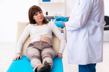 Yaralı genç kadın genç erkek doktoru ziyaret ediyor.