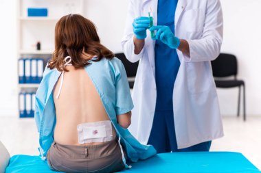 Yaralı genç kadın genç erkek doktoru ziyaret ediyor.