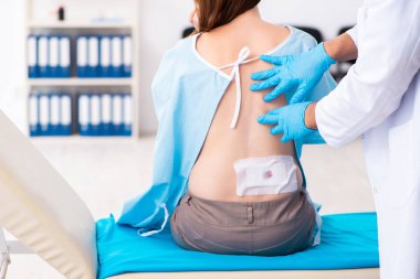 Yaralı genç kadın genç erkek doktoru ziyaret ediyor.