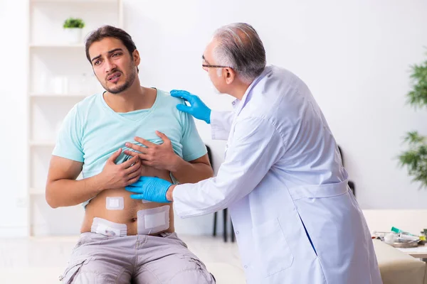 Yaralı genç adam deneyimli erkek doktoru ziyaret ediyor. — Stok fotoğraf