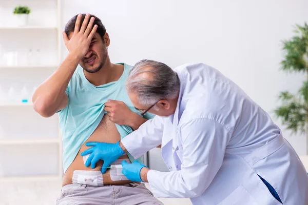 Joven lesionado visitando a un médico experimentado —  Fotos de Stock