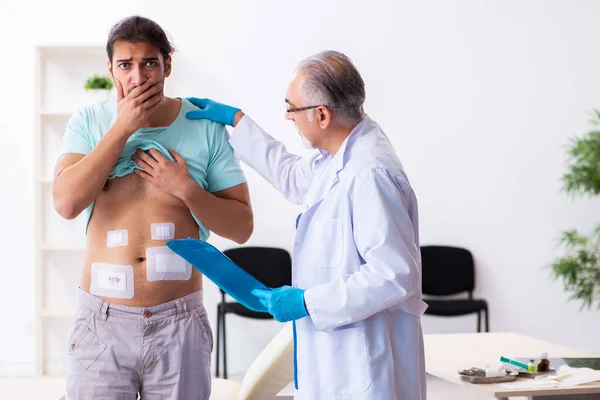 Joven lesionado visitando a un médico experimentado —  Fotos de Stock