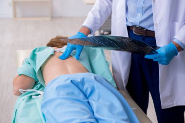 Genç sırtı yaralı kadın, erkek doktor masörünü ziyaret ediyor.