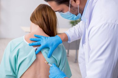 Genç sırtı yaralı kadın, erkek doktor masörünü ziyaret ediyor.
