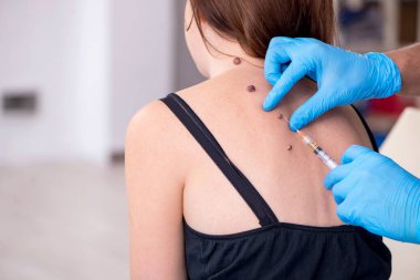 Genç bir kadın erkek doktor dermatoloğunu ziyaret ediyor.