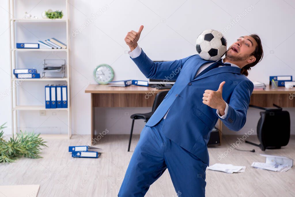 Young male employee playing football in the office