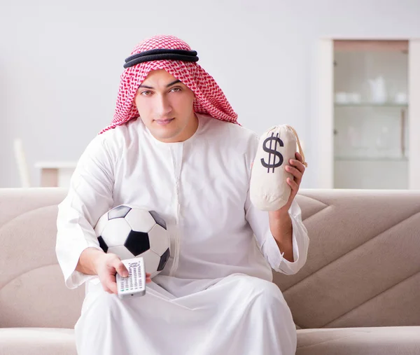 Young arab man watching football sitting on sofa — Stock Photo, Image