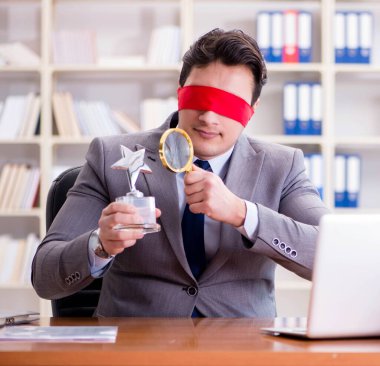 Ofiste masasında oturan gözü bağlı iş adamı.