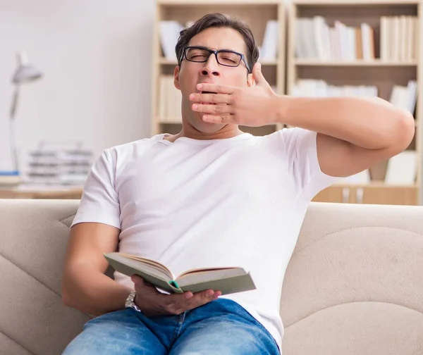 Человек читает книгу сидя на диване — стоковое фото